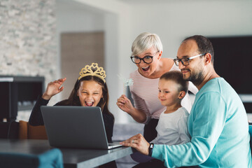 Fototapeta premium Cheerful caucasian family of four communicating with grandparents over video call