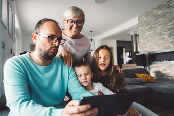 Caucasian family of four taking to grandparents over video call