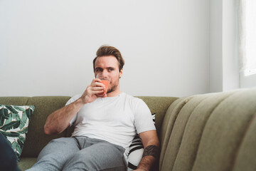 Caucasian man enjoying his breakfast smoothie on the sofa