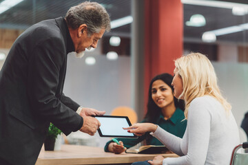 Disabled blonde woman on wheelchair helping her senior manager with the use of technology