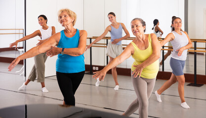 Dancing active women engaged in a group class practice energetic dance in a modern dance studio
