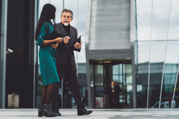 Senior man and Indian woman walking side by side to a meeting