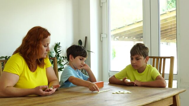 Mother shows kids how to play domino, board game and time together