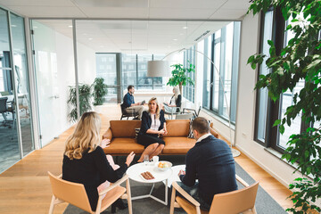 Business people having multiple meetings in modern office with glass walls