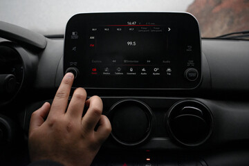 Detail of a hand turning on the radio in his modern car