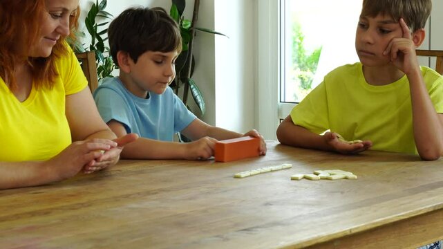 Mother shows kids how to play domino, board game and time together