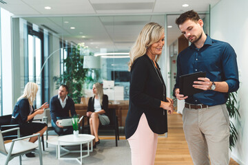 Businessman showing something on a digital tablet to a senior woman CEO