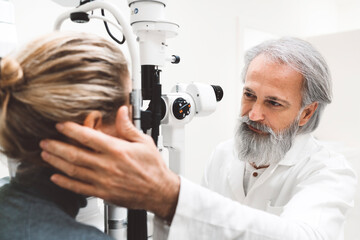 Optometrist doing sight testing for patient. Patient at doctor for eye examination.