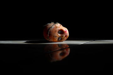 Reflection of a creepy doll in a dark room, a creepy doll covered in dried blood