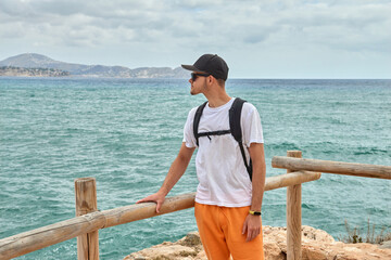 Summer Vacation in Spain: Hiker Admiring Ocean View from High Cliff Under Sunny Blue Sky in Calpe. Enchanting Spanish Coastal View Calpe Rocky Beach Turquoise Waves Summer Sky Perfect Vacation Spot