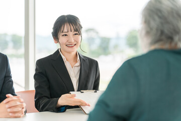 シニア女性に書類の説明をするビジネスウーマンとビジネスマン
