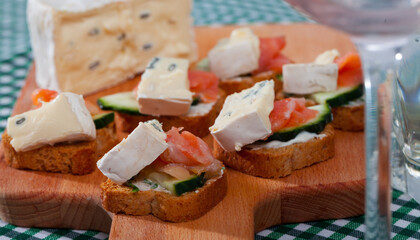 Delicious canapes on toasted bread with smoked salmon, cambozola, cucumber and creamy sauce on...