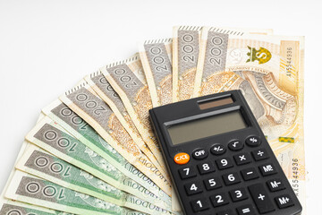Fototapeta premium Polish PLN banknotes spread out on a white background, with a black calculator on them