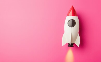 A small toy rocket is blasting off, emitting flames, set against a bright magenta backdrop
