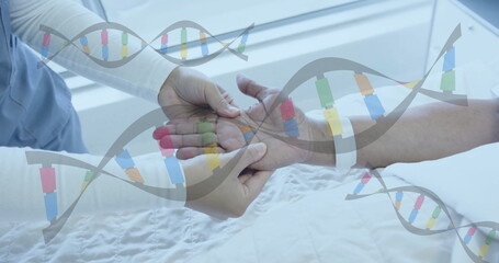 Image of dna strands over diverse female doctor massaging hand of senior female patient