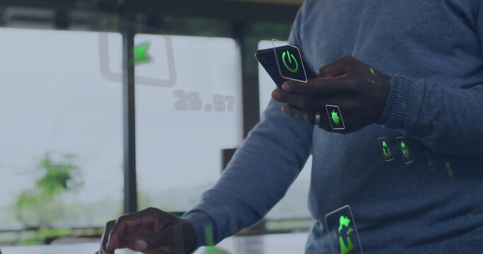 Image of energy and ecology icons over senior african american man using smartphone at home