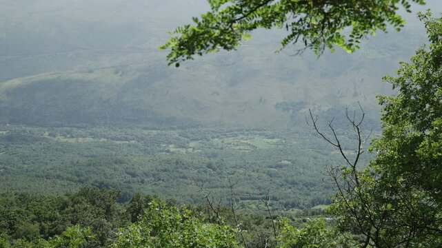 Land seen from high up of village and green trees in a valley in Montenegro. Beautiful view of green hills and valleys in the Balkan country of Montenegro