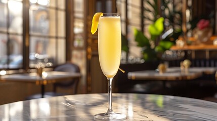A classic French 75 champagne cocktail served in a flute, with a lemon twist garnish. The flute is set on a polished marble table with a Parisian caf&eacute; in the background, 