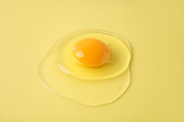 One raw egg on yellow background, closeup