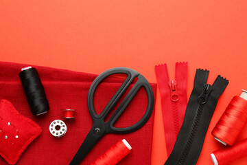 Flat lay composition with different sewing supplies on coral background. Space for text