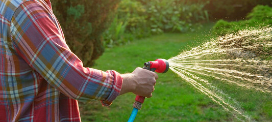 Man watering lawn with hose in backyard, closeup