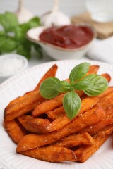 Sweet potato fries and basil on table, closeup