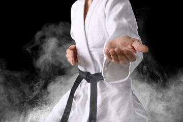 Karate fighter in smoke on black background, closeup