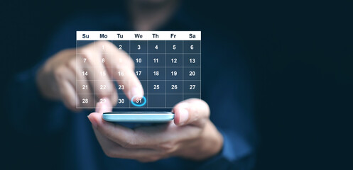 Planning and time management concept. A man manages his time using virtual screen calendar interface on his smartphone to highlight the date to remind him about important work, meeting, or agenda