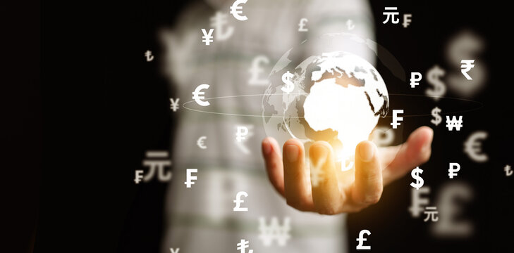 Global currency exchange and money transfer concept. Hand holding a globe with international currencies symbols. Financial technology for business.