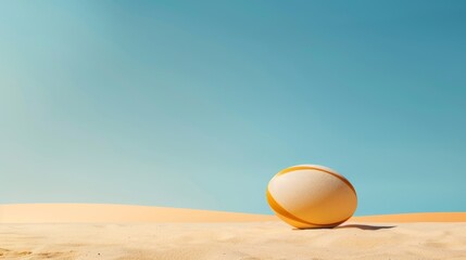 A single rugby ball rests on a sandy beach, with a clear blue sky behind it. This evokes a sense of peace, relaxation, and summertime fun, perfect for a vacation getaway.