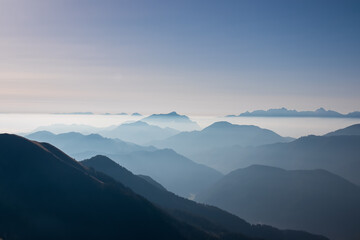 Serene alpine landscape at dawn in Gailtal Alpen, Carinthia, Austria, Europe. Silhouette of majestic hazy mountain ridges of Julian Alps. Peaceful tranquil atmosphere in Austrian Alps. Wanderlust