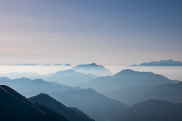 Serene alpine landscape at dawn in Gailtal Alpen, Carinthia, Austria, Europe. Silhouette of majestic hazy mountain ridges of Julian Alps. Peaceful tranquil atmosphere in Austrian Alps. Wanderlust