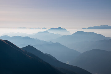 Serene alpine landscape at dawn in Gailtal Alpen, Carinthia, Austria, Europe. Silhouette of majestic hazy mountain ridges of Julian Alps. Peaceful tranquil atmosphere in Austrian Alps. Wanderlust