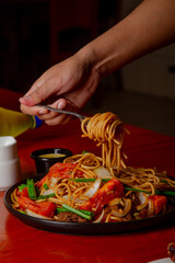 Tallarín saltado enrollado en mano