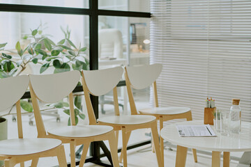 Modern office waiting area featuring white chairs and a round table with clean lines and minimalist decor