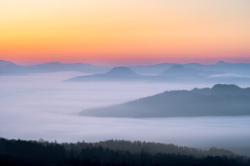 上から見下ろす雲と山の風景。霧のように漂う雲が幻想的な印象を描いている。