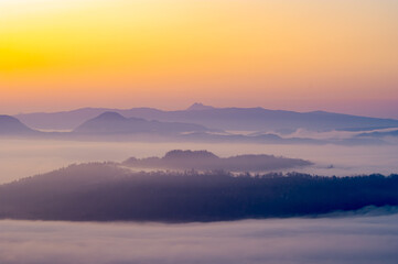 上から見下ろす雲と山の風景。霧のように漂う雲が幻想的な印象を描いている。