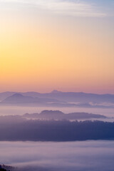 上から見下ろす雲と山の風景。霧のように漂う雲が幻想的な印象を描いている。