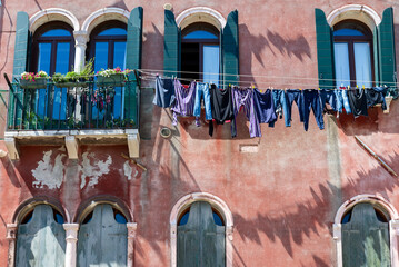Laundry hanging from a clothes line outside a window on the street in Venice, Italy