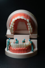 Miniature figurines of surgeons working on a large model of human teeth