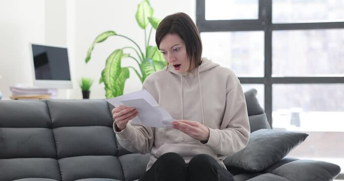 Upset sad woman reading important documents sitting on sofa