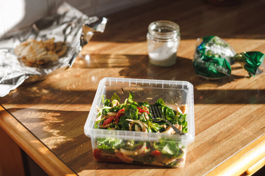 Healthy salad in a tupper ware on a rustic wooden table. Homemade take-away food.