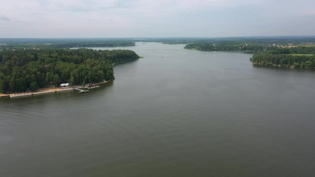 drone flies above wide river on cloudy summer day, boat dock near, Speedboats