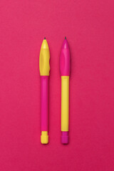 Bright Neon Yellow and Pink Pens - Colorful Stationery on Vibrant Red Background