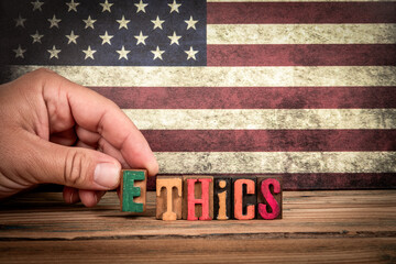 ETHICS. Colorful letters of the alphabet on a wooden texture table