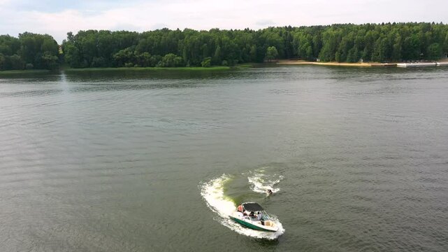 man riding surfboard holding boat tow rope but falls into water, surfing boat