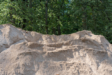 A pile of sand and dirt in a forest setting, ready for construction or landscaping work