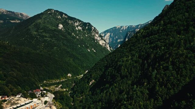 A mountain range with a small town in the valley below in peja kosovo rugova canyon. Mountains are lush and green,the valley is dotted with houses. The scene is peaceful and serene aerial drone view