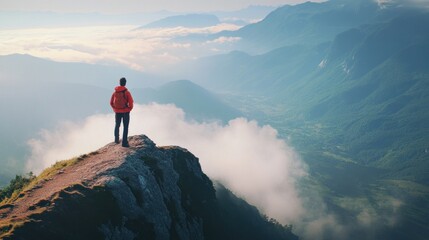 A lone hiker contemplates the vast landscape of mountains and clouds