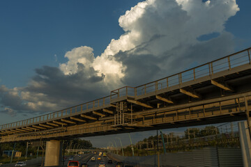 A bridge over a highway with a large cloud in the sky